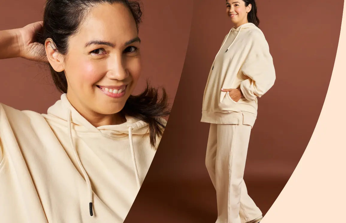 Woman wearing a beige hoodie and pants against a brown background. Womene Australian women's loungewear  collection